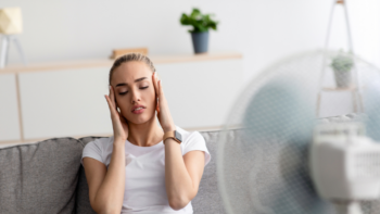 žena s bolesťou hlavy na ktorú fúka ventilátor