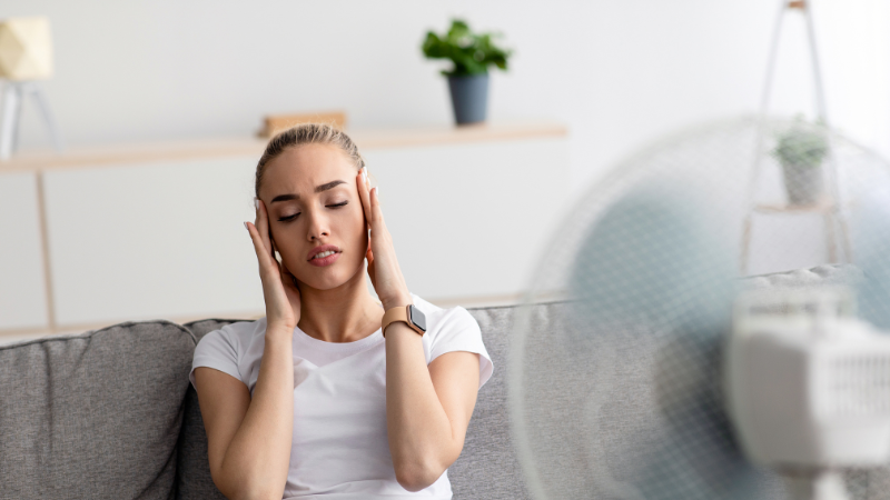 žena s bolesťou hlavy na ktorú fúka ventilátor